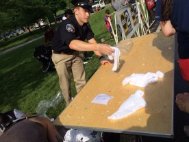 Volunteer police officer soaking cold towels for us runners.