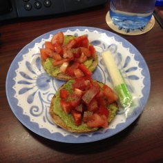 Bagel thins topped with mashed avocado and tomatoes with a cheese stick